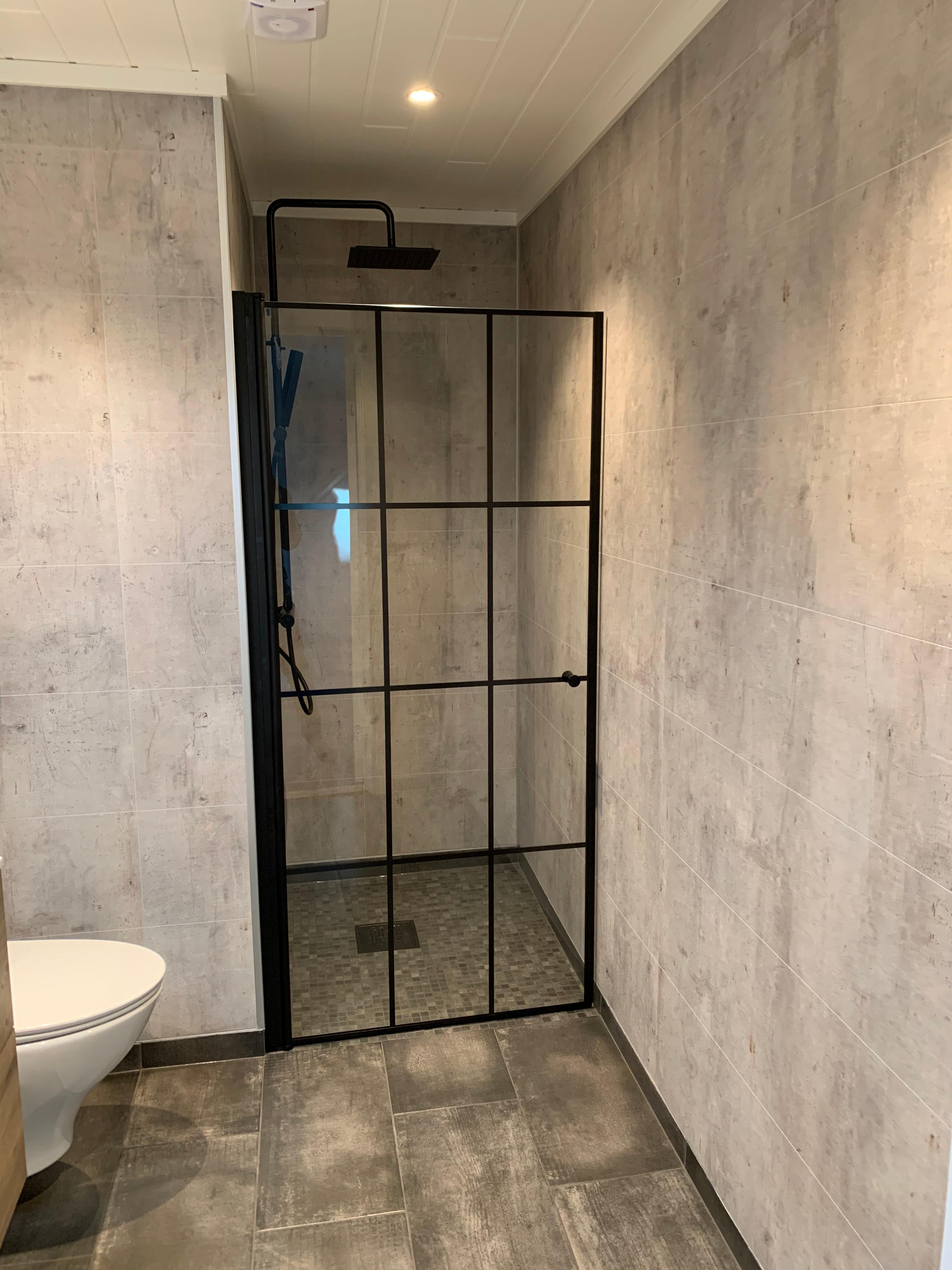 A finished bathroom with a black-framed glass shower wall