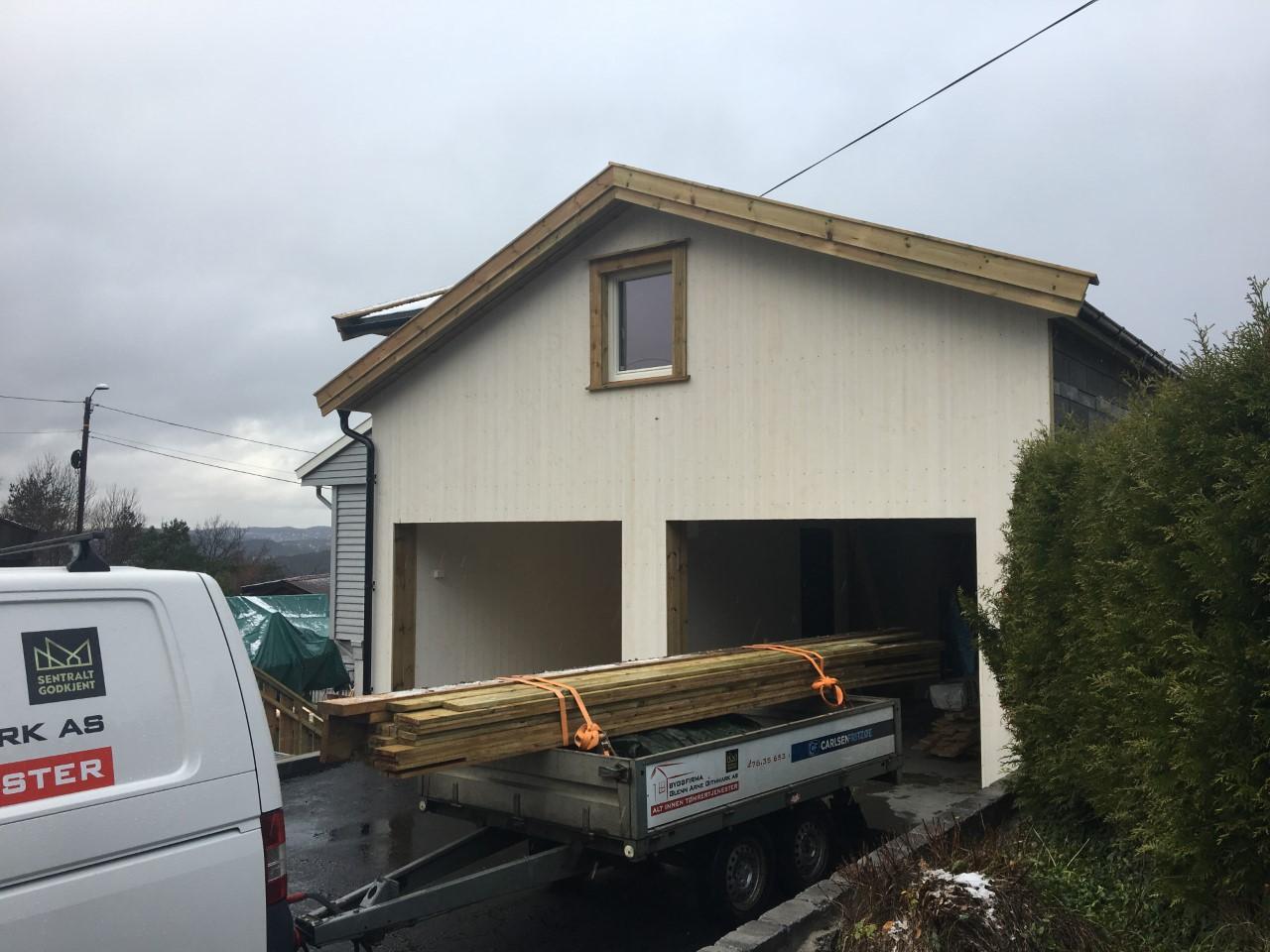 A double garage with timber loaded on a trailer in front