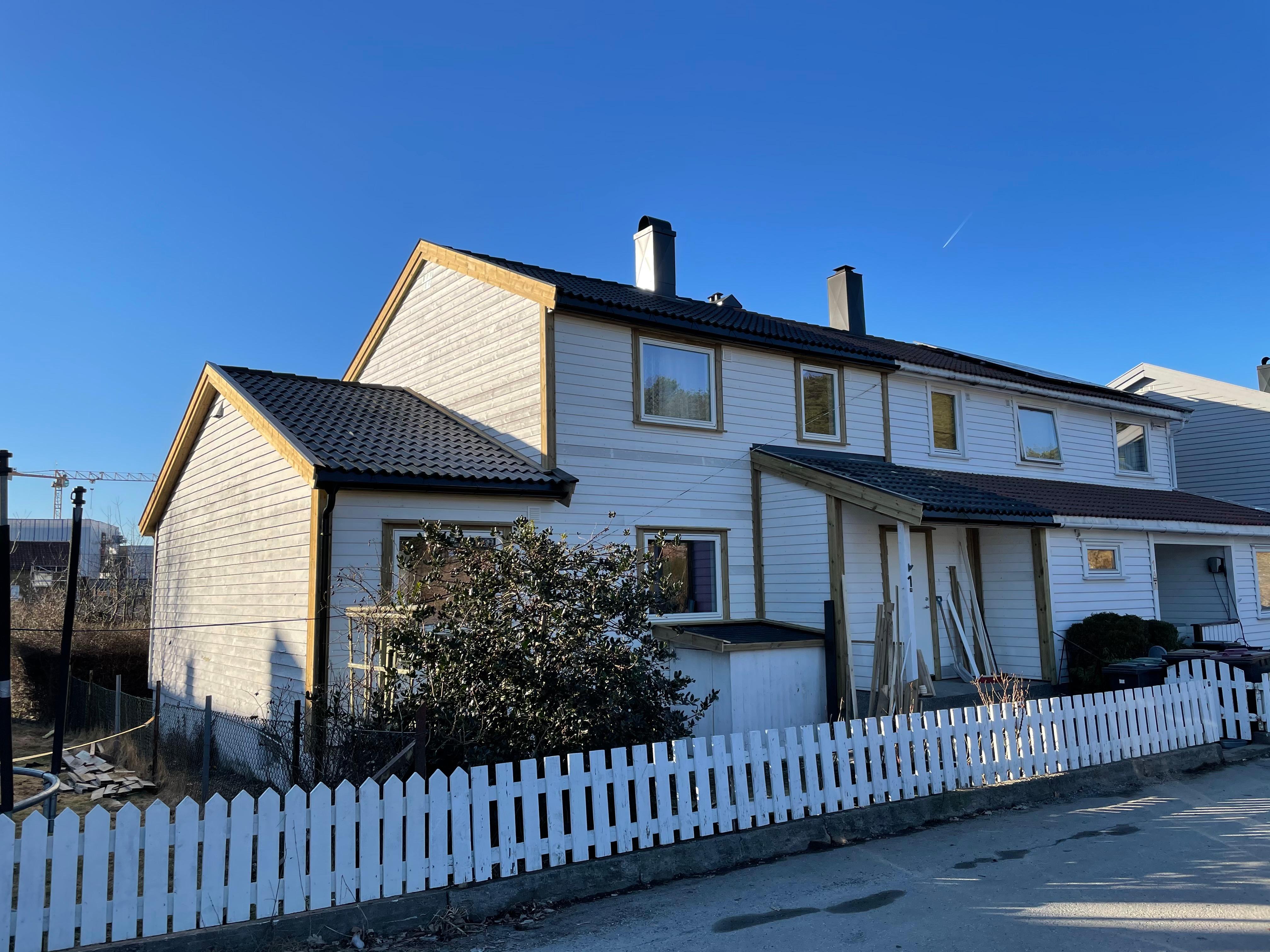 A white semi-detached house with a picket fence under a blue sky